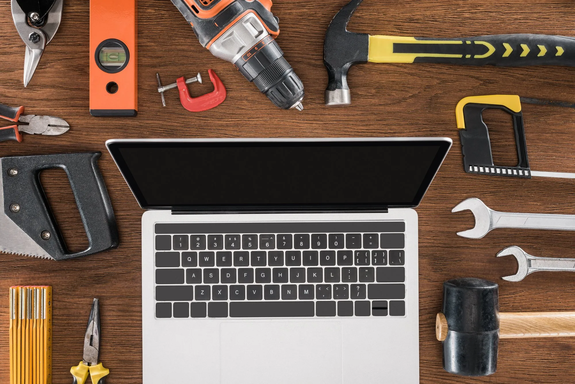 Laptop surrounded by tools on a wooden desk